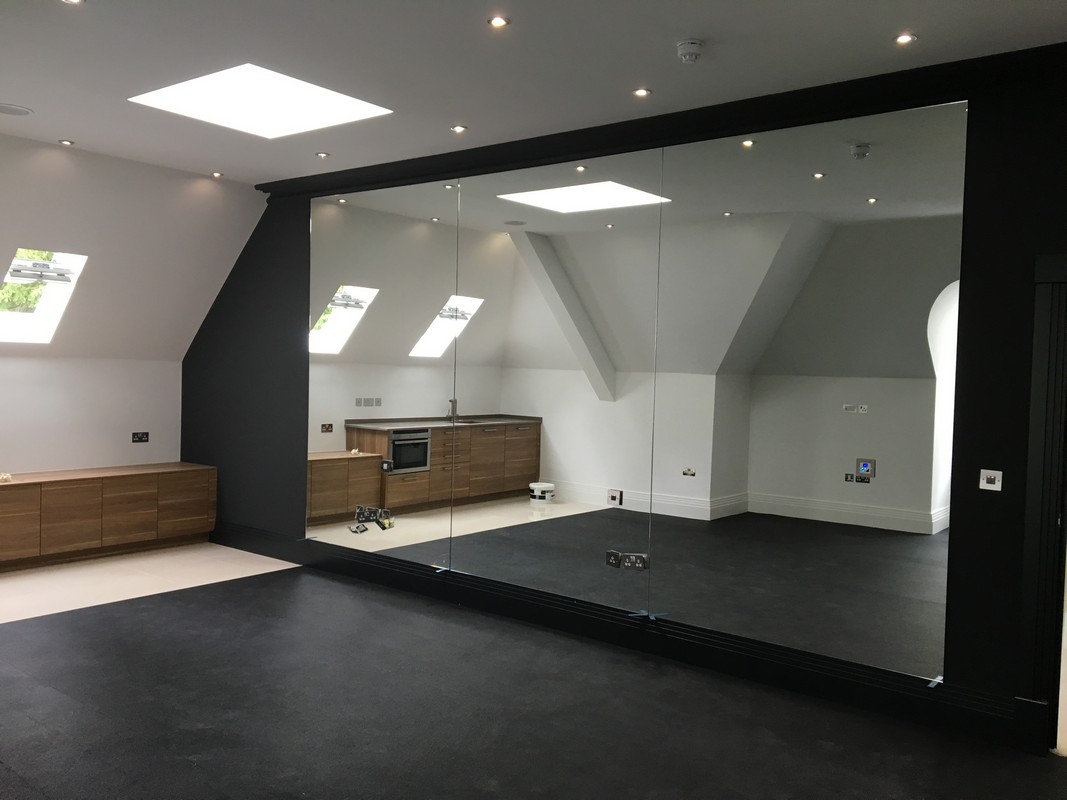 Frameless glass wall dividing loft conversion in Winchmore Hill